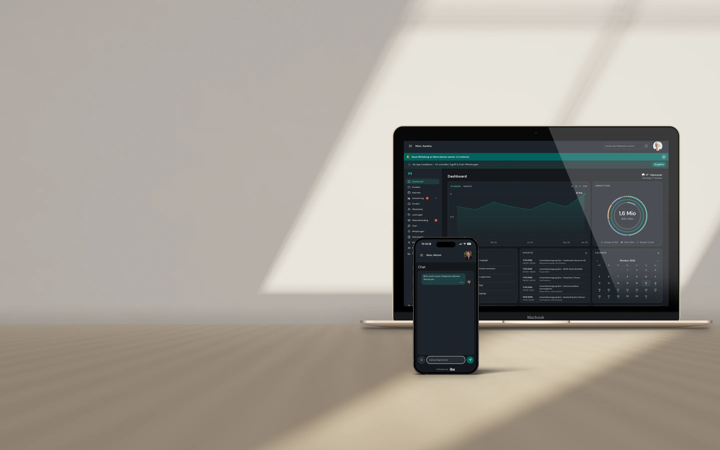 MacBook und iPhone auf einem Eichentisch im Tageslicht mit der Wieland-Plattform: Dashboard mit Stunden, Umsatz, Einsätzen und Kalender, auf dem Smartphone der Team-Chat.