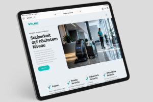 Fachkraft der Wieland Gebäudereinigung reinigt mit Reinigungsroboter und Wagen einen modernen Bürofoyer-Bodenigung reinigt mit Reinigungsroboter und Wagen einen modernen Bürofoyer-Boden