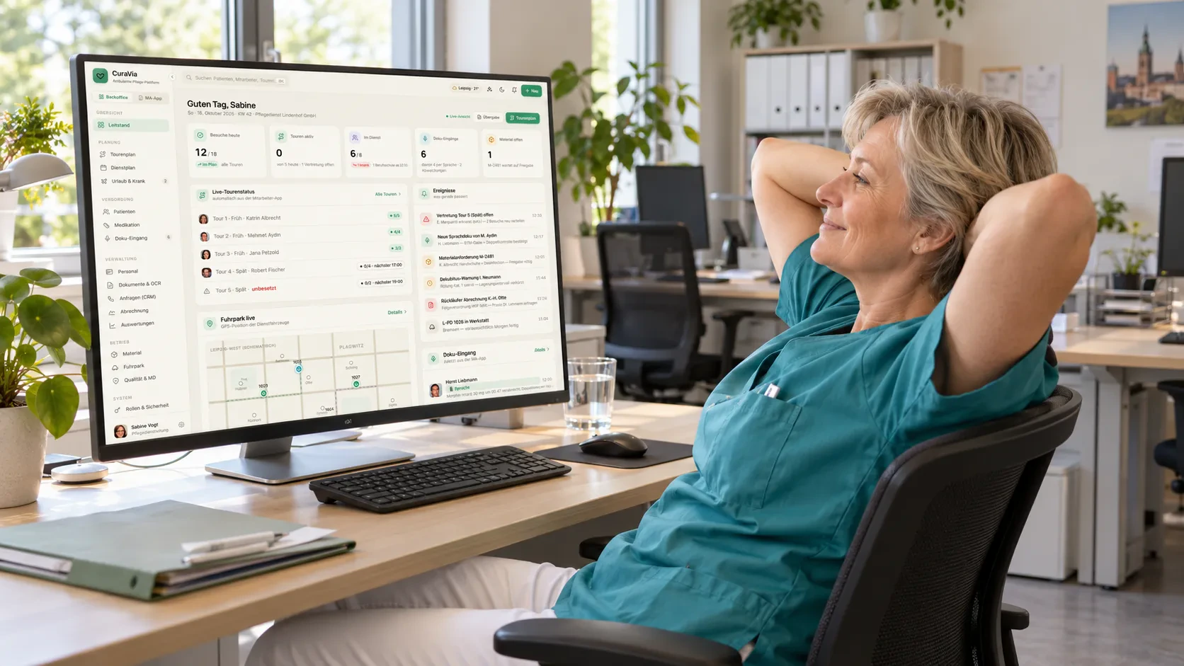 Mitarbeiterin lehnt sich entspannt am Schreibtisch zurück, auf dem Bildschirm ein übersichtliches Dashboard.