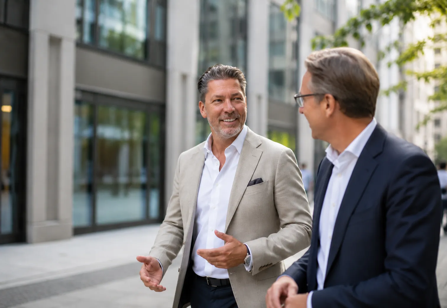 Michel Winkler im Gespräch mit einem Geschäftspartner vor modernen Bürogebäuden.